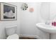 Cozy powder room features a modern pedestal sink, toilet, and decorative wall art at 10863 Gardenova Ave, Las Vegas, NV 89166