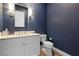 Chic powder room with a textured navy blue wall, modern sconces, and a white vanity at 11015 Sanctuary Cove Ct, Las Vegas, NV 89135