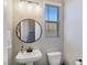 Clean half-bathroom with a modern vanity, circular mirror, and window providing natural light at 11739 Emerald Lake Ave, Las Vegas, NV 89138