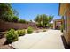 Backyard with desert landscaping, concrete patio, gravel, mature trees, and block wall at 1830 Lake Wales St, Henderson, NV 89052