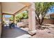 Covered patio with a dark table set in a backyard with a gravel landscape and mature tree at 1830 Lake Wales St, Henderson, NV 89052