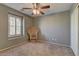 Neutral carpeted bedroom with a wicker chair, window with shutters, and ceiling fan at 1904 Via Firenze, Henderson, NV 89044