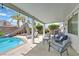 Relaxing covered patio with comfortable seating overlooking the pool, slide, and manicured landscaping at 2011 Mountain Sunset Ave, North Las Vegas, NV 89031