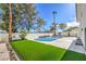 Backyard pool area featuring a refreshing pool, concrete patio, lush lawn, privacy wall, and multiple palm trees at 2611 Siesta Ave, Las Vegas, NV 89121