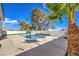 Backyard pool area featuring a refreshing pool, concrete patio, privacy wall, and palm trees under a bright blue sky at 2611 Siesta Ave, Las Vegas, NV 89121