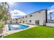 Backyard pool area featuring a refreshing pool, concrete patio, lush artificial lawn, two-story home, and palm trees at 2611 Siesta Ave, Las Vegas, NV 89121