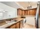 Kitchen with brown cabinets, granite countertops, stainless sink, and tile flooring, with access to living room at 2838 Geary Pl # 4017, Las Vegas, NV 89109