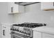 Close-up of a stainless steel gas range with white cabinets and a decorative tile backsplash at 363 El Pico Dr, Henderson, NV 89014