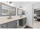 Bright bathroom features a double sink vanity with grey cabinets, quartz countertop and modern fixtures and a shower at 4212 Helens Pouroff Ave, North Las Vegas, NV 89085