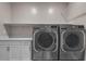Bright laundry room featuring modern gray washer and dryer machines and white cabinets at 5927 Villa Loma St, Las Vegas, NV 89148