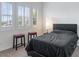 Bright bedroom featuring a bed with black duvet, two stools and shuttered windows at 6421 Winecup St, Las Vegas, NV 89149