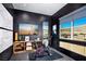 Home gym boasts black brick walls, exercise equipment, and scenic views from large windows at 658 Agate Bridge St, Las Vegas, NV 89138
