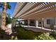 Inviting backyard featuring a covered patio, desert landscaping, and lush green foliage at 7250 Birkland Ct, Las Vegas, NV 89117