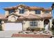 Two-story home showcasing a well-manicured yard, two-car garage, and a distinctive tile roof at 8982 Emerald Waters Ct, Las Vegas, NV 89147