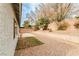 Side view of the backyard showcasing a patio, shrubs, and neutral colored exterior walls at 9514 Teton Vista Ave, Las Vegas, NV 89117