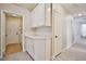 Hallway with storage cabinets, white trim, and light wood floors leading to the laundry room at 9514 Teton Vista Ave, Las Vegas, NV 89117
