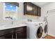 This laundry room is equipped with a sink, washer, dryer, dark cabinets and view of the mountains at 7017 Pearl Hilltop Ct, Las Vegas, NV 89148