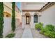 Inviting front entryway featuring an arched doorway, tiled path, lush plants, and stone covered front yard at 1013 Brinkman St, Las Vegas, NV 89138