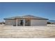 Exterior rear shot of a home featuring a covered patio, light stucco, and a dark tiled roof in a desert landscape at 1131 Lupin St, Pahrump, NV 89048