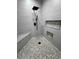 Modern shower with gray tile, hexagon tile floor and black rain shower head at 1131 Lupin St, Pahrump, NV 89048