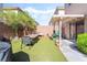 Wide angle view of a backyard featuring artificial grass, outdoor dining table, and patio cover at 135 Manor House Ave, Las Vegas, NV 89123