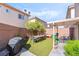 Backyard with artificial grass, a patio cover, a bbq and an outdoor dining table with four chairs at 135 Manor House Ave, Las Vegas, NV 89123