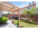 Backyard featuring artificial grass, a patio cover, an outdoor dining table, and lots of trees at 135 Manor House Ave, Las Vegas, NV 89123