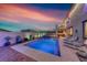 A serene backyard featuring a pool, spa, lounge chairs, and a dining area against a colorful sunset backdrop at 1523 Great Sands St, Boulder City, NV 89005