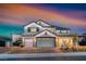 Beautiful two-story home featuring a well-manicured lawn, three-car garage, and covered front porch, illuminated by outdoor lighting at 1523 Great Sands St, Boulder City, NV 89005