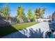 Expansive backyard featuring lush artificial grass, mature trees, patio, and privacy wall perfect for outdoor enjoyment at 1553 Bright View Dr, Las Vegas, NV 89119