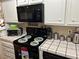 The kitchen features black appliances, tile countertops, and overhead microwave at 1866 Camino Verde Ln, Las Vegas, NV 89119