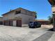 Rear exterior view featuring garages, a balcony, and a car parked in the parking lot at 2657 Kline Cir, Las Vegas, NV 89121