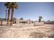 Home's backyard featuring palm trees, a white-walled privacy enclosure, and dirt landscaping at 2755 E Russell Rd, Las Vegas, NV 89120