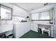 Bright laundry room features a front-load washer and dryer, built-in cabinets, and a sink near a window at 2755 E Russell Rd, Las Vegas, NV 89120