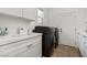 Convenient laundry room with modern, front loading washer and dryer and bright white cabinets and counters at 2797 Turtle Head Peak Dr, Las Vegas, NV 89135