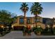 Elegant two-story home with a well-manicured front yard, mature palm trees, and a stylish arched entryway at 2837 Turtle Head Peak Dr, Las Vegas, NV 89135