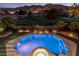 Aerial shot of the backyard pool area features a jacuzzi, night lighting, and golf course and mountain views at 2837 Turtle Head Peak Dr, Las Vegas, NV 89135