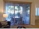Living room view of outdoor patio with table and chairs through sliding glass door and vertical blinds at 35 Emerald Dunes Cir, Henderson, NV 89052
