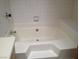 Clean white bathtub with tile surround and built in seating at 4050 Pacific Harbors Dr # 214, Las Vegas, NV 89121