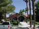 Clubhouse exterior with a red tile roof, desert landscaping, and mature palm trees at 4050 Pacific Harbors Dr # 214, Las Vegas, NV 89121