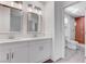 Bright bathroom featuring double vanity and a separate enclosed shower with red brick wall at 5811 Pack Trl, Las Vegas, NV 89118