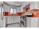 Modern kitchen with white cabinets, stainless steel appliances, quartz countertops, and red backsplash at 5811 Pack Trl, Las Vegas, NV 89118