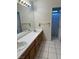 Well-lit bathroom featuring double sinks with wood cabinets and tiled floors and a doorway to the shower area at 6208 Mandarin Dr, Las Vegas, NV 89108