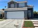 Two-story home with a blue-gray exterior, white garage door, and desert landscaping at 6208 Mandarin Dr, Las Vegas, NV 89108