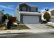 Two-story home with a blue-gray exterior, white garage door, and desert landscaping at 6208 Mandarin Dr, Las Vegas, NV 89108