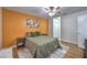 Comfortable bedroom with an orange accent wall, ceiling fan, and two floral art pieces at 6920 Singing Dunes Ln, Las Vegas, NV 89145