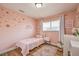 Pink bedroom design with flower decals, a white bed frame, and a window with blinds at 6920 Singing Dunes Ln, Las Vegas, NV 89145