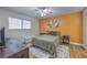 Comfortable bedroom with an orange accent wall, light colored carpet, and a large window for natural light at 6920 Singing Dunes Ln, Las Vegas, NV 89145