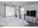 Bedroom with lots of natural light, full-length mirror, and dresser with a television at 7468 Wellfleet Bay Ave, Las Vegas, NV 89179
