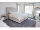 Sun-filled bedroom features a large window, tufted headboard, and gray carpeting at 7468 Wellfleet Bay Ave, Las Vegas, NV 89179